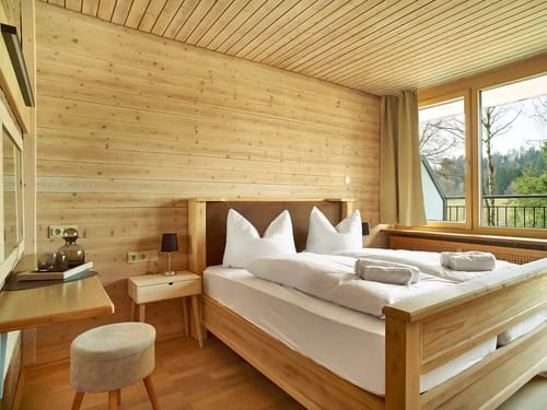 Gemütliches Schlafzimmer mit Holzverkleidung und großem Fenster mit Aussicht