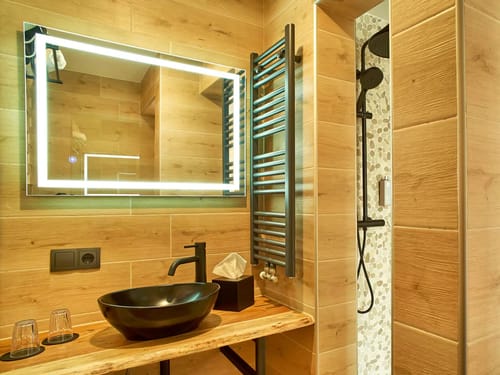 Modernes Badezimmer mit beleuchtetem Spiegel und Regendusche