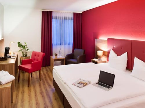 Geräumiges Zimmer mit Schreibtisch, Stühlen und TV