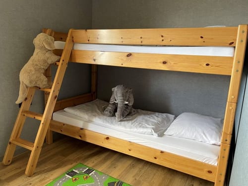 Kinderzimmer mit Hochbett aus Holz und Kuscheltieren.