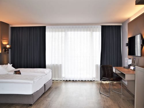 Modernes Hotelzimmer mit Doppelbett und Arbeitsbereich.