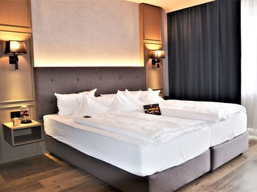 Modernes Hotelzimmer mit komfortablem Doppelbett, eleganter Einrichtung und sanfter Beleuchtung.