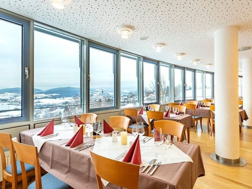 Elegantes Restaurant mit großer Fensterfront und Blick auf schneebedeckte Landschaft.