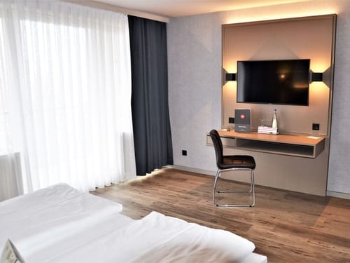 Entdecken Sie ein elegantes Hotelzimmer mit modernen Annehmlichkeiten, darunter ein Schreibtisch für Ihre Arbeit und ein Flachbildfernseher zur Unterhaltung. Perfekt für Geschäftsreisende und Urlauber.