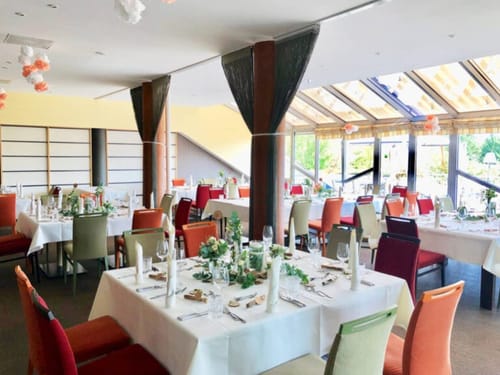 Eleganter Hochzeitsempfangsbereich mit festlich gedeckten Tischen und stimmungsvollem Sonnenlicht.