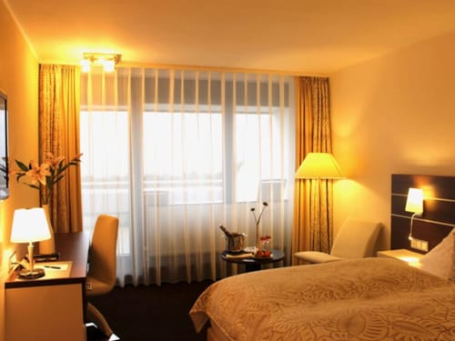 Entspannen Sie sich in diesem stilvollen Hotelzimmer, das mit einem komfortablen Doppelbett, einem eleganten Schreibtisch und großen, lichtdurchfluteten Fenstern ausgestattet ist. Perfekt für Geschäftsreisende und Urlauber.