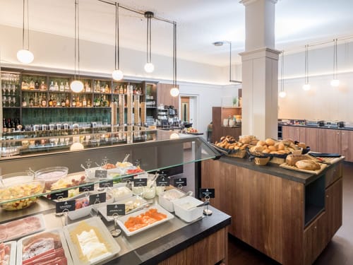 Frühstücksbuffet mit verschiedenen Speisen und Brotauswahl in modernem Restaurant.