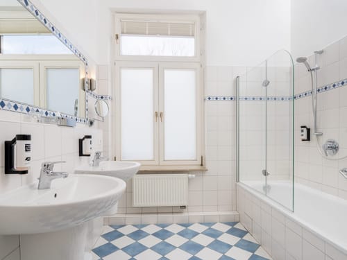 Modernes Badezimmer mit zwei Waschbecken, Badewanne und blauen Fliesen.