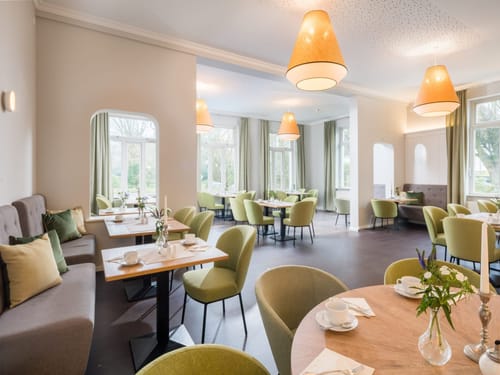 Modernes Restaurant-Interieur mit eleganter Einrichtung und grünen Sitzplätzen.