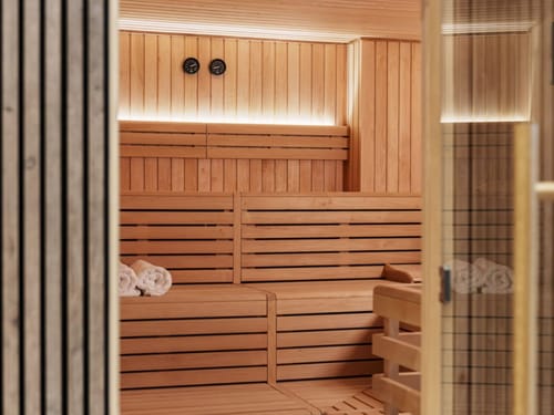 Moderne Holzsauna mit Handtüchern und beleuchtetem Innenraum