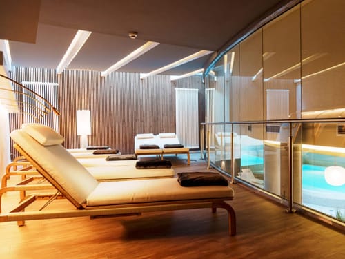 Entspannungsbereich eines modernen Spas mit Liegestühlen und großer Glaswand.