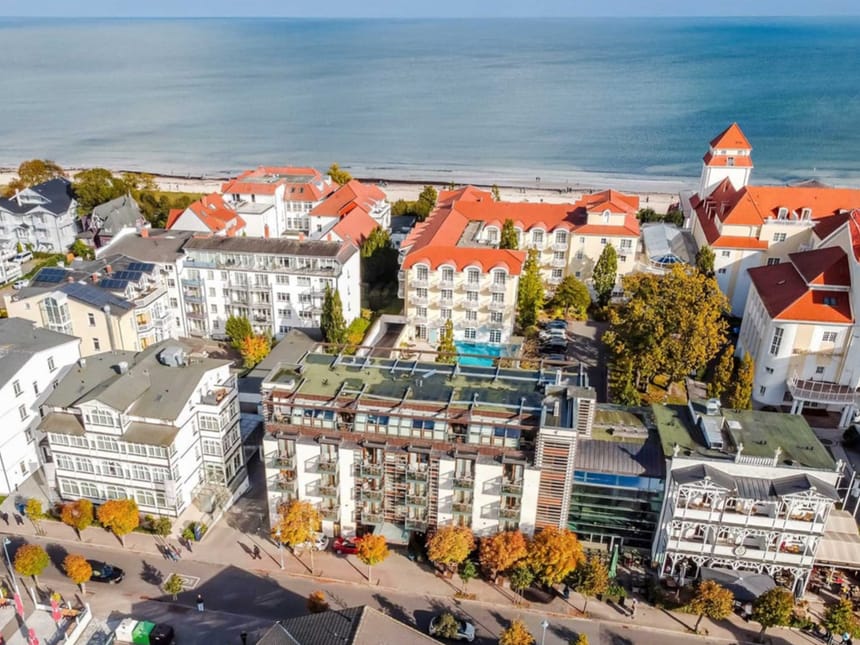 Luftaufnahme von Küstenstadt mit charakteristischen roten Dächern und Ostsee im Hintergrund.