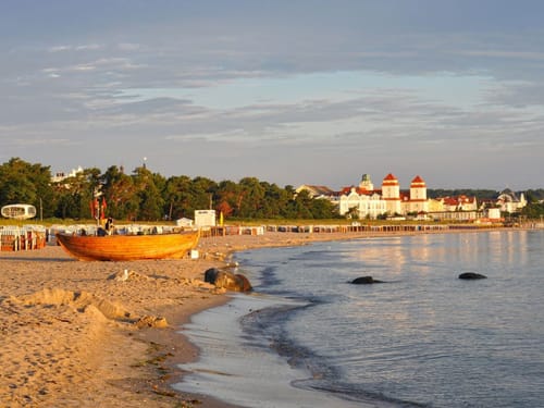 Malerischer Strand mit historischem Gebäude in Binz, Rügen, bei Sonnenuntergang.