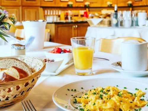 Entdecken Sie das perfekte Frühstück mit frischem Rührei, knusprigen Brezen und einem Glas Orangensaft. Starten Sie Ihren Tag mit Genuss und Energie.