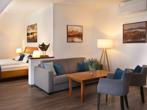 Entdecken Sie ein elegantes Hotelzimmer mit einer komfortablen Sitzecke und einem einladenden Doppelbett. Die harmonische Einrichtung und die warmen Farben schaffen eine entspannende Atmosphäre.