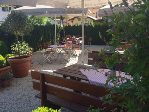 Gemütlicher Biergarten mit Holzbänken und Sonnenschirmen.