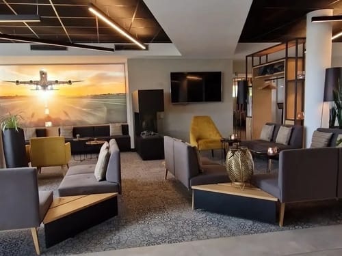 Moderner Lounge-Bereich mit stilvoller Einrichtung und großem Wandbild eines Flugzeugs bei Sonnenuntergang.