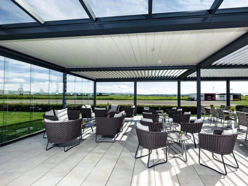 Moderne Terrasse mit Korbmöbeln und Glaswänden.