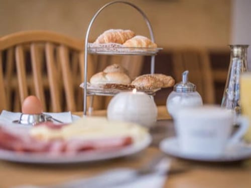 Gemütliches Frühstück mit Croissants und Brötchen auf einem Tisch.