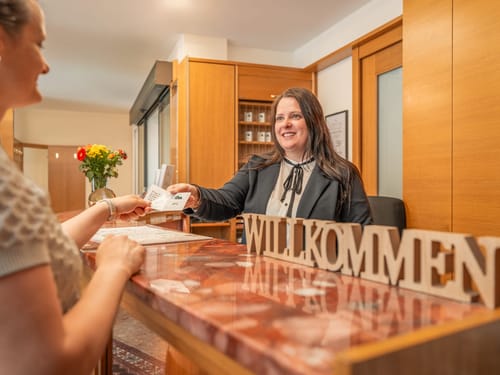 Empfangsdame im Hotel an der Rezeption mit Willkommensschild