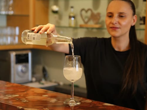 Frau gießt Weißwein in ein Glas an einer Theke.