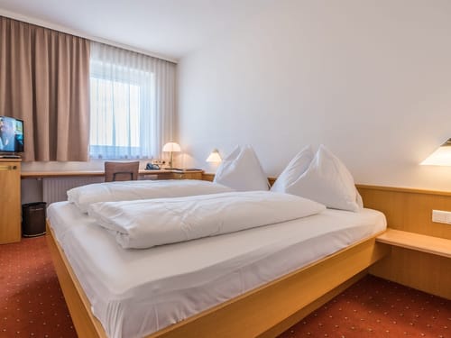 Gemütliches Hotelzimmer mit Doppelbett, Schreibtisch und Fernseher