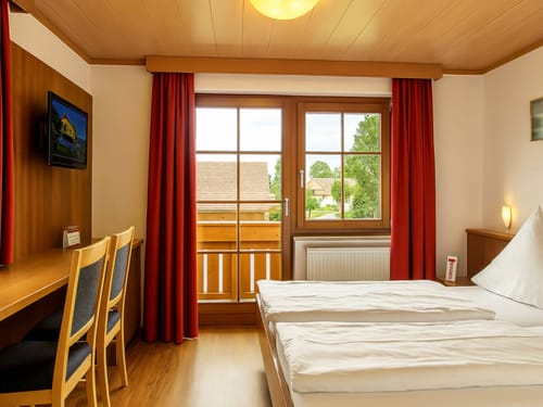 Gemütliches Hotelzimmer mit Balkon und Holzverkleidung
