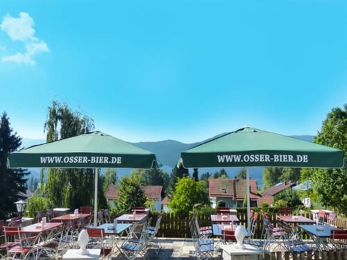 Biergarten mit Osser-Bier Sonnenschirmen in malerischer Landschaft