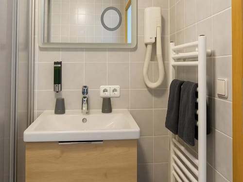 Modernes Badezimmer mit Waschtisch, Spiegel, Haartrockner und Handtuchhalter.
