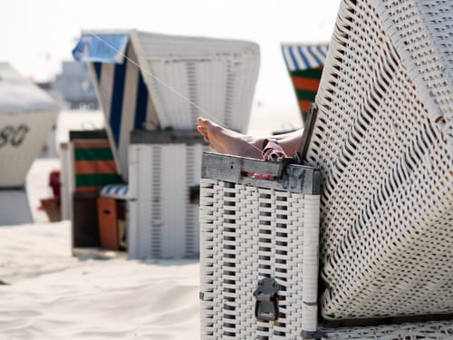 Entspannte Füße auf einem Strandkorb am Sandstrand in Deutschland.