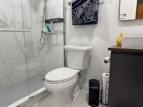 Modernes Badezimmer mit Marmordusche und weißen Fliesen.