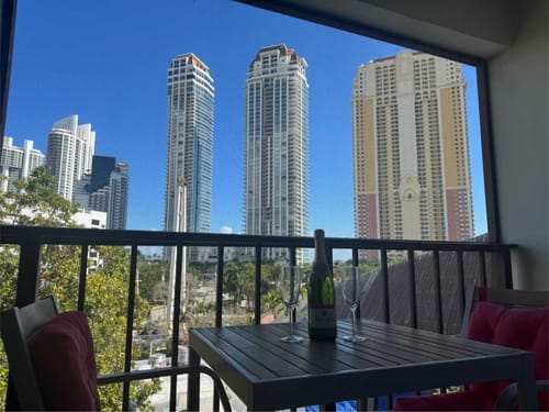 Moderne Hochhäuser und gemütlicher Balkon mit Tisch und Champagner in einer Stadtansicht.