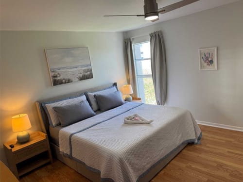 Modernes, lichtdurchflutetes Schlafzimmer mit einem gemütlichen Doppelbett, stilvoller Bettwäsche und dekorativen Nachttischlampen.
