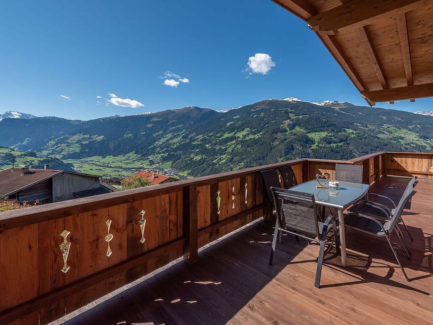 Atemberaubende Aussicht von einer Holzterrasse auf die Alpen und das Tal.