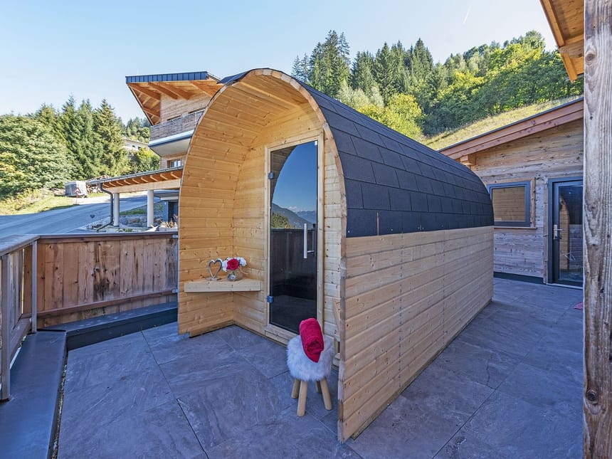 Holzsauna auf einer Terrasse mit Blick auf eine bewaldete Berglandschaft