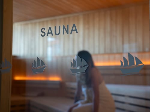 Innenansicht einer Sauna mit einer entspannten Person und dekorativen Glasaufklebern.