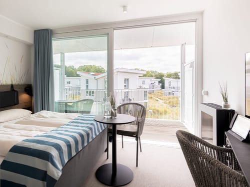 Modernes Hotelzimmer mit Balkon und Blick auf eine grüne Wohnanlage