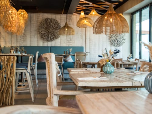 Gemütlich eingerichtetes Restaurant mit rustikalen Holztischen und stilvollen Lampen.