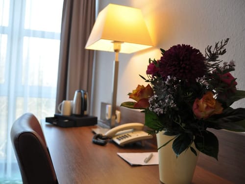 Hotelzimmer mit Schreibtisch, Blumen und Lampe