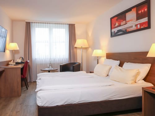 Modernes Hotelzimmer mit gemütlichem Doppelbett, Schreibtisch und Sitzgelegenheit