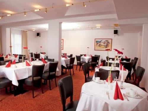 Elegantes Restaurant mit gedeckten Tischen und roter Dekoration