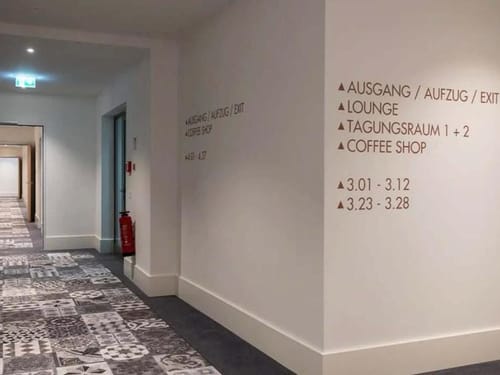 Moderner Hotelkorridor mit Wandbeschriftungen und Teppichboden