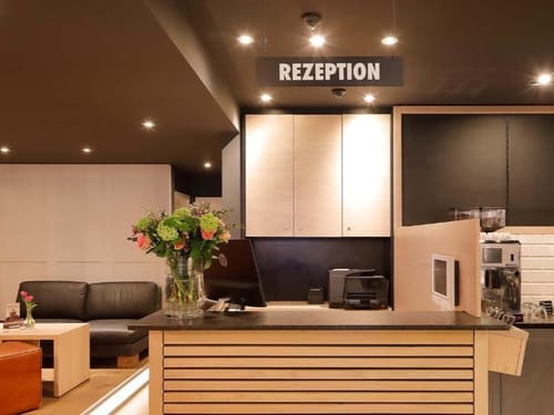 Moderne Hotelrezeption mit Blumenarrangement und bequemen Sitzgelegenheiten.