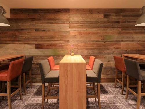 Gemütlicher Innenraum mit Holztischen und modernen Barstühlen