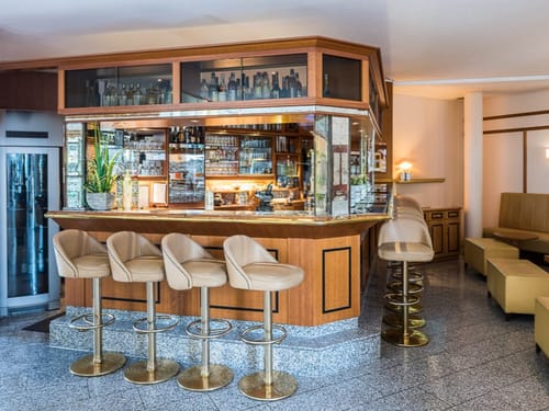 Hotelbar mit gepolsterten Barhockern und einer breiten Auswahl an Getränken