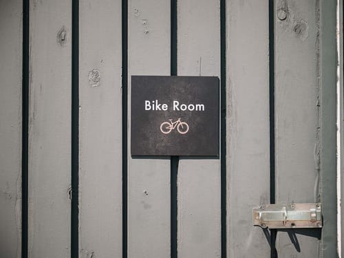 Schild "Bike Room" an einer grauen Holztür