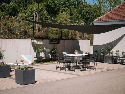Moderner Gartenbereich mit stilvollen Gartenmöbeln, Sonnensegel und Pflanzen