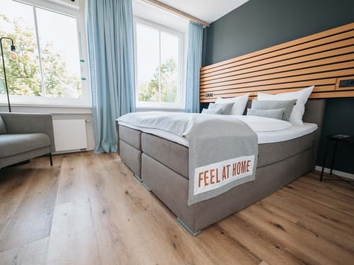 Modern eingerichtetes Schlafzimmer mit großem Fenster und gemütlichem Bett