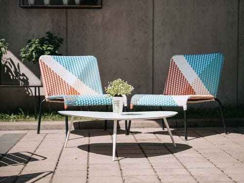 Bunte Gartenstühle und ein moderner Couchtisch auf einer Terrasse