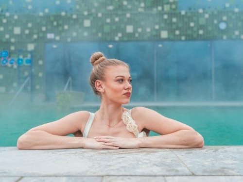 Frau entspannt im Thermalbad vor moderner Architektur